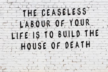 Beyaz tuğla duvar arkaplanına siyah düşünceli bir yazı.