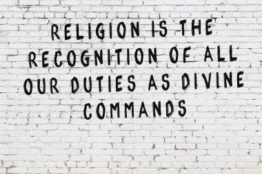 Beyaz tuğla duvara zekice alıntılar yazılı siyah bir yazı.