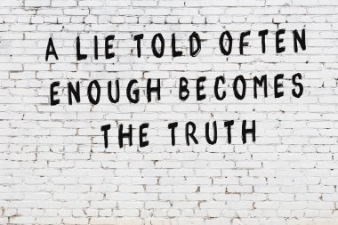 Beyaz tuğla duvara zekice alıntılar yazılı siyah bir yazı.