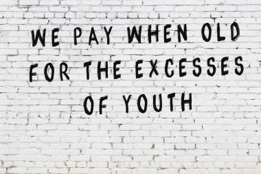 Beyaz tuğla duvara zekice alıntılar yazılı siyah bir yazı.