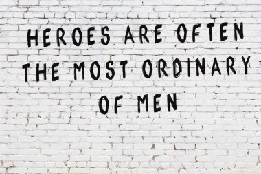 Beyaz tuğla duvara zekice alıntılar yazılı siyah bir yazı.