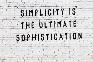 Beyaz tuğla duvara zekice alıntılar yazılı siyah bir yazı.