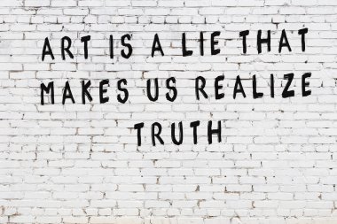 Beyaz tuğla duvar arkaplanına siyah düşünceli bir yazı.