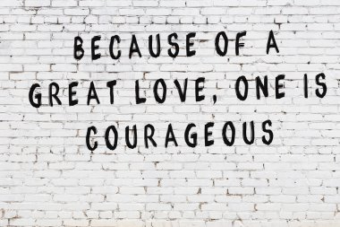 Beyaz tuğla duvara zekice alıntılar yazılı siyah bir yazı.