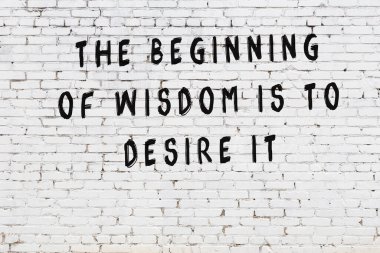 Beyaz tuğla duvara zekice alıntılar yazılı siyah bir yazı.