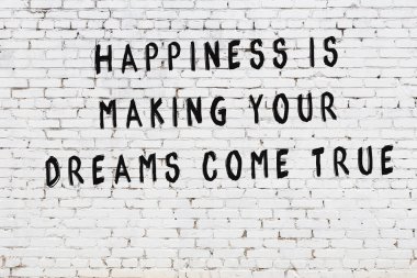 Beyaz tuğla duvara zekice alıntılar yazılı siyah bir yazı.