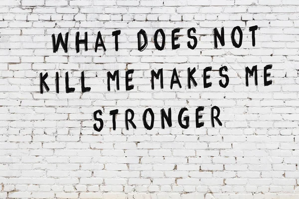 Beyaz tuğla duvara zekice alıntılar yazılı siyah bir yazı.