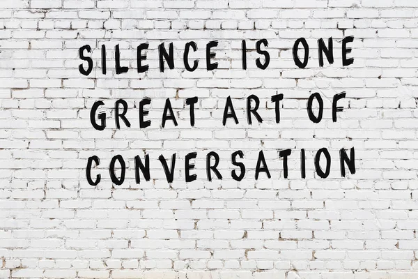 Beyaz tuğla duvara zekice alıntılar yazılı siyah bir yazı.