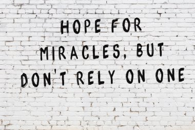 Beyaz tuğla duvar arkaplanına siyah düşünceli bir yazı.