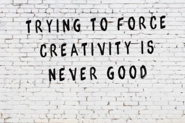 Beyaz tuğla duvar arkaplanına siyah düşünceli bir yazı.