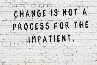 Beyaz tuğla duvar arkaplanına siyah düşünceli bir yazı.