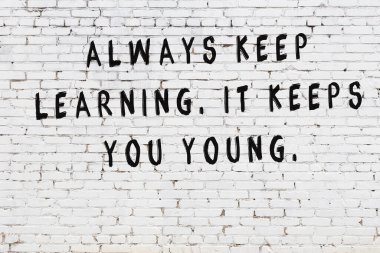 Bilgece alıntıların yazılı olduğu siyah boyanmış beyaz tuğla duvar