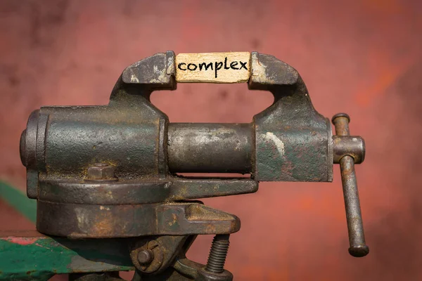 Vice grip tool knijpen een plank met het woord complex — Stockfoto