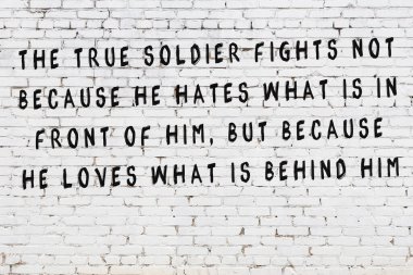 Beyaz tuğla duvara zekice alıntılar yazılı siyah bir yazı.