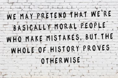 Beyaz tuğla duvara zekice alıntılar yazılı siyah bir yazı.