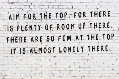 Beyaz tuğla duvara zekice alıntılar yazılı siyah bir yazı.