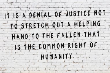 Beyaz tuğla duvara zekice alıntılar yazılı siyah bir yazı.