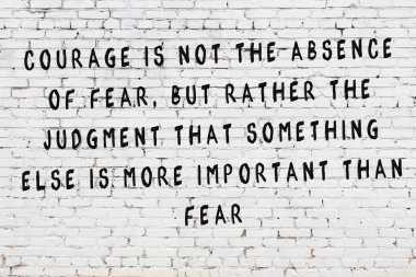 Beyaz tuğla duvara zekice alıntılar yazılı siyah bir yazı.