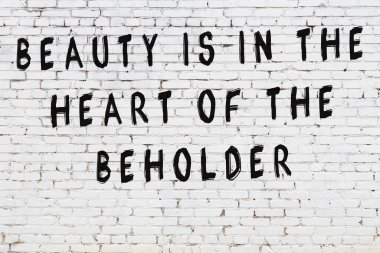 Beyaz tuğla duvara zekice alıntılar yazılı siyah bir yazı.