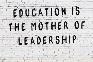 Beyaz tuğla duvara zekice alıntılar yazılı siyah bir yazı.