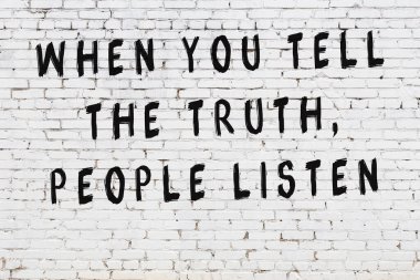 Beyaz tuğla duvara zekice alıntılar yazılı siyah bir yazı.