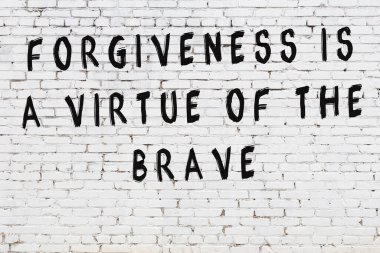 Beyaz tuğla duvara zekice alıntılar yazılı siyah bir yazı.