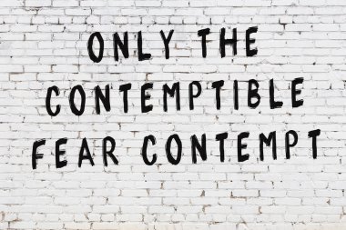Beyaz tuğla duvara zekice alıntılar yazılı siyah bir yazı.
