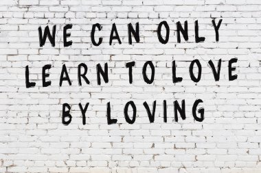 Beyaz tuğla duvar arkaplanına siyah düşünceli bir yazı.