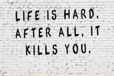 Beyaz tuğla duvar arkaplanına siyah düşünceli bir yazı.