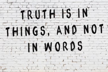 Beyaz tuğla duvar arkaplanına siyah düşünceli bir yazı.