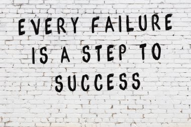 Beyaz tuğla duvara zekice alıntılar yazılı siyah bir yazı.