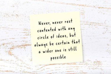 Ahşap duvardaki sarı yapışkan notta bilgece bir alıntı var.