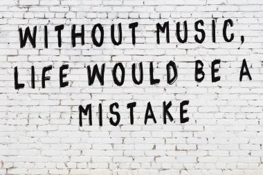 Beyaz tuğla duvara zekice alıntılar yazılı siyah bir yazı.