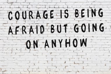 Beyaz tuğla duvara zekice alıntılar yazılı siyah bir yazı.