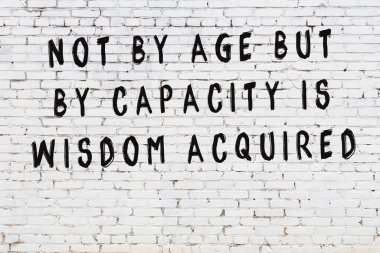 Beyaz tuğla duvara zekice alıntılar yazılı siyah bir yazı.