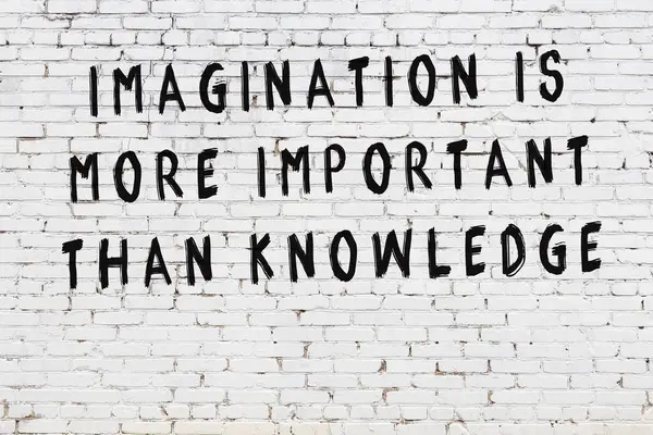 Beyaz tuğla duvara zekice alıntılar yazılı siyah bir yazı.