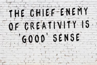 Beyaz tuğla duvar arkaplanına siyah düşünceli bir yazı.