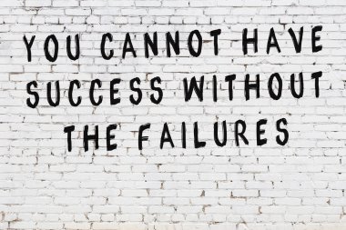 Beyaz tuğla duvar arkaplanına siyah düşünceli bir yazı.