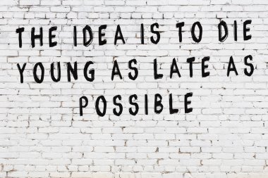 Beyaz tuğla duvar arkaplanına siyah düşünceli bir yazı.