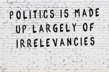 Beyaz tuğla duvara zekice alıntılar yazılı siyah bir yazı.