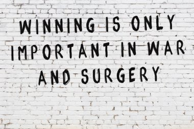 Beyaz tuğla duvara zekice alıntılar yazılı siyah bir yazı.