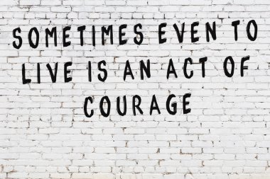 Beyaz tuğla duvara zekice alıntılar yazılı siyah bir yazı.