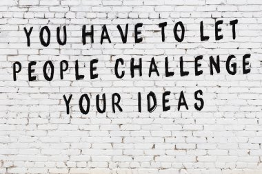 Beyaz tuğla duvar arkaplanına siyah düşünceli bir yazı.