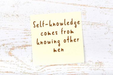 Ahşap duvardaki sarı yapışkan notta bilgece bir alıntı var.