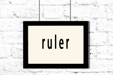 Beyaz tuğla duvarda asılı siyah çerçeve ve yazıt cetveli