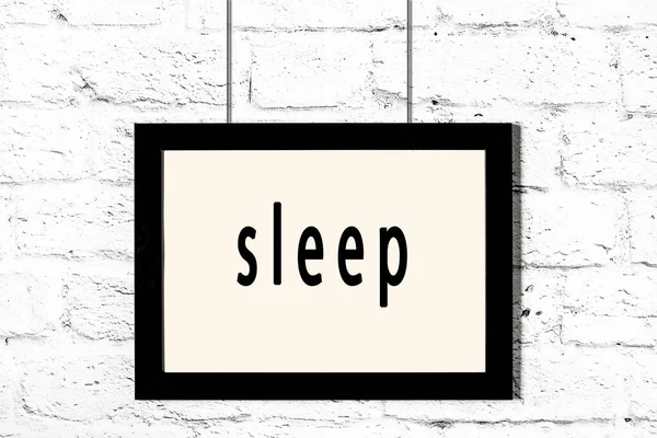 Black frame hanging on white brick wall with inscription sleep — Stock Photo, Image