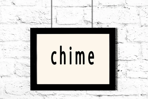 Black frame hanging on white brick wall with inscription chime — Stock Photo, Image