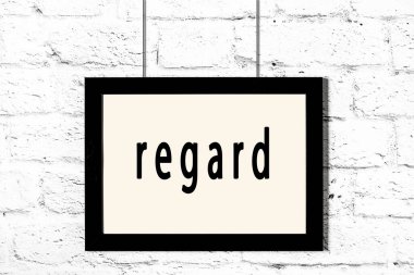 Beyaz tuğla duvarda asılı siyah çerçeve.