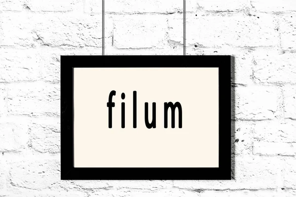 Schwarzer Rahmen hängt an weißer Ziegelwand mit Inschrift Filum — Stockfoto