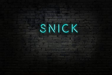 Üzerinde yazı olan neon levhası tuğla duvara çarpıyor.